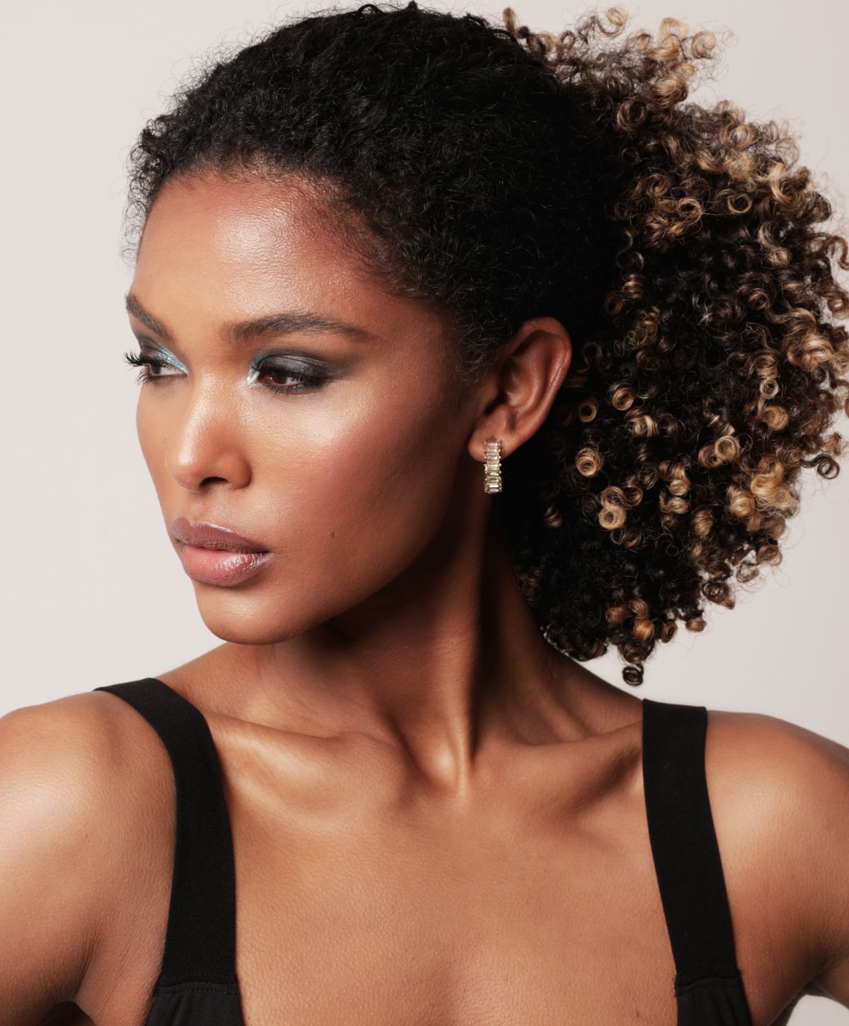 Model with curly hair and elegant earrings.